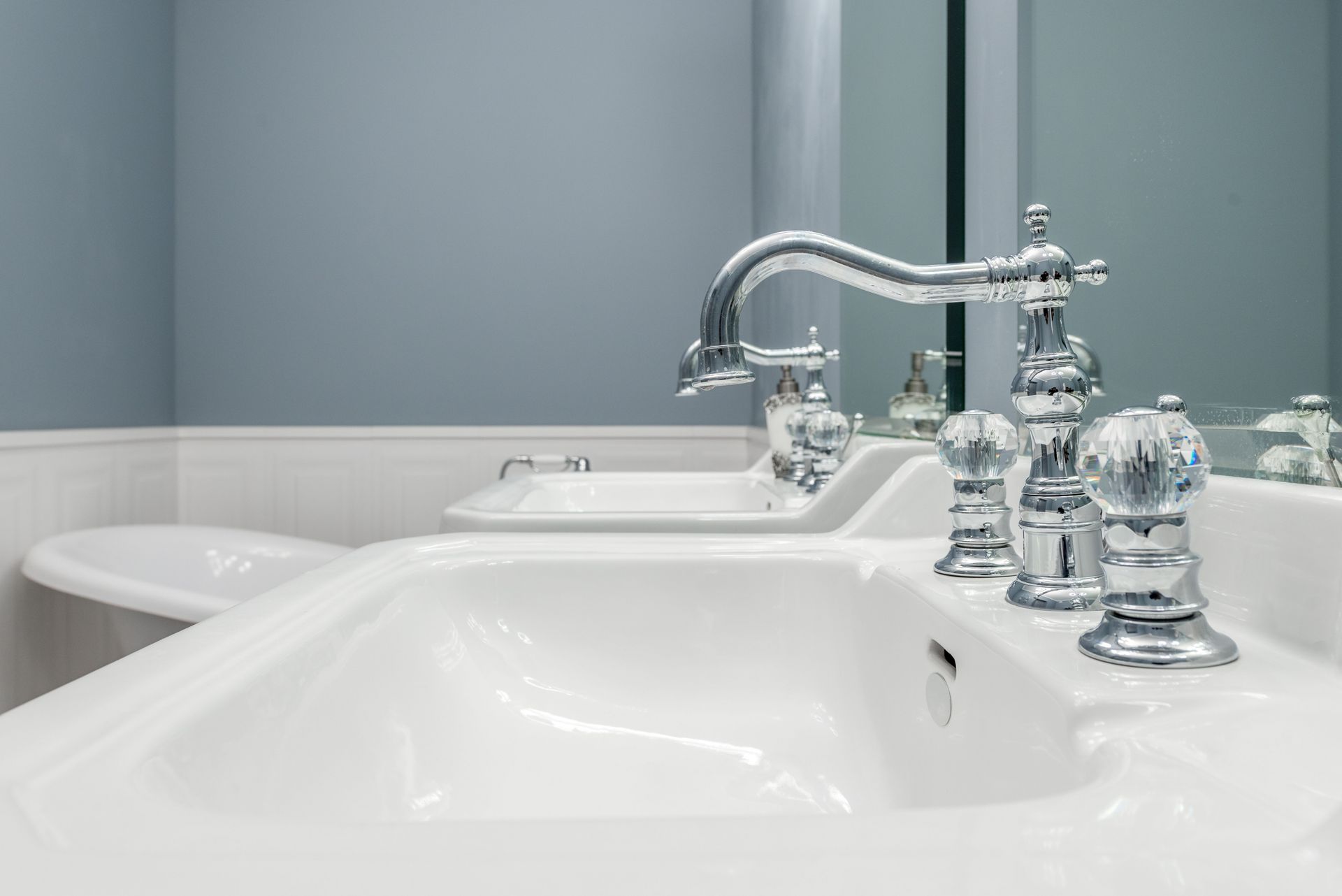 Clean white sinks with stylish metal faucets in light bathroom in luxury apartment